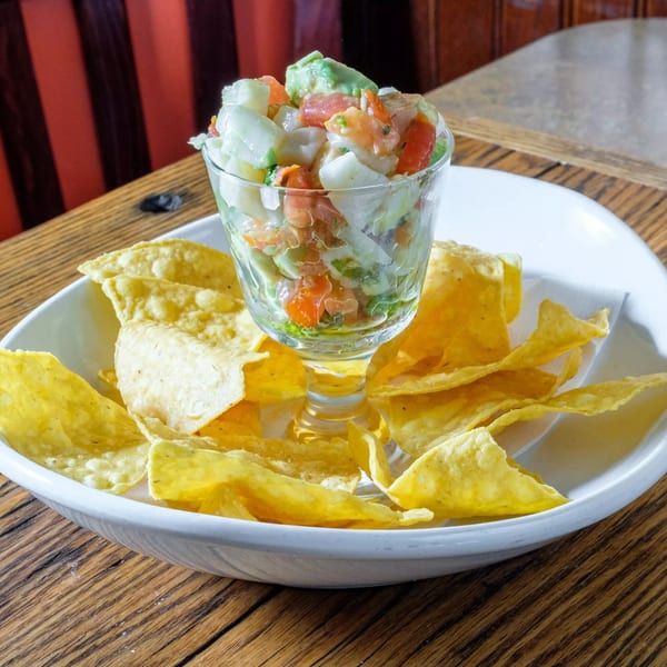 Tortilla Press Cantina's ceviche in a glass with tortilla chips on a white plate.